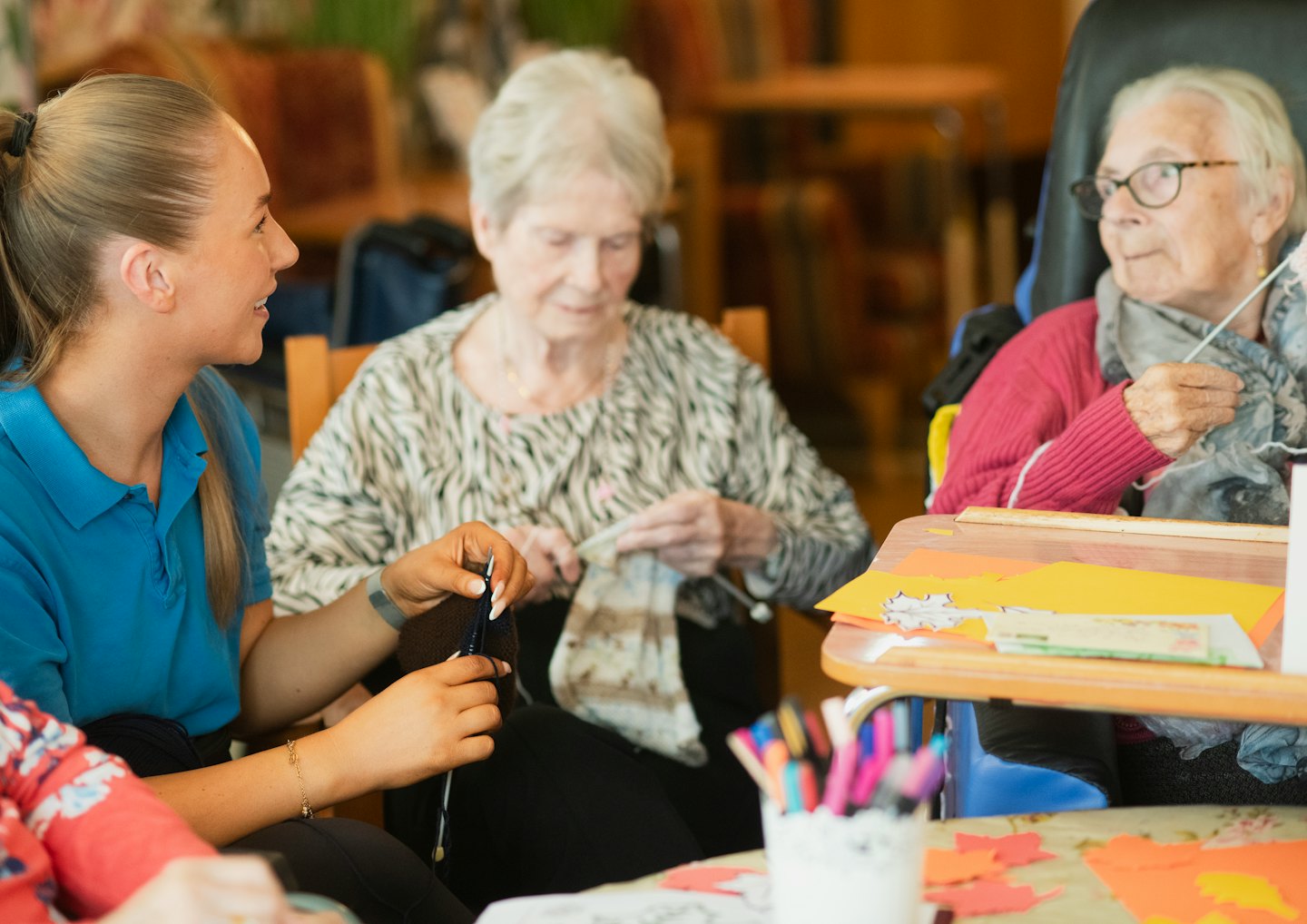 Volunteer knitting and crafting with two elderly women.