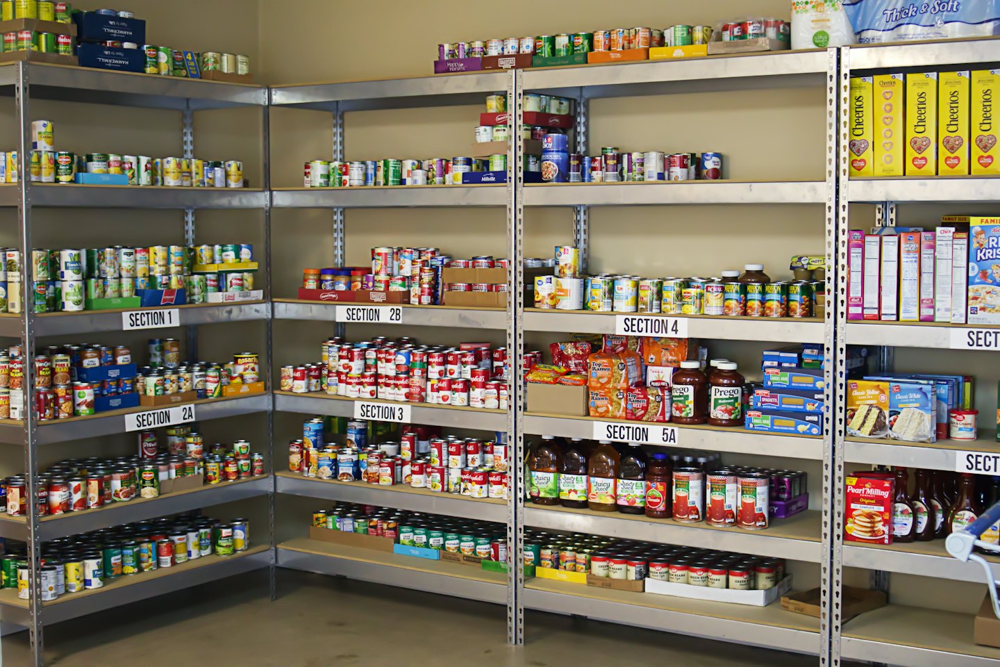 Organized pantry shelves stocked with donated canned goods and groceries.