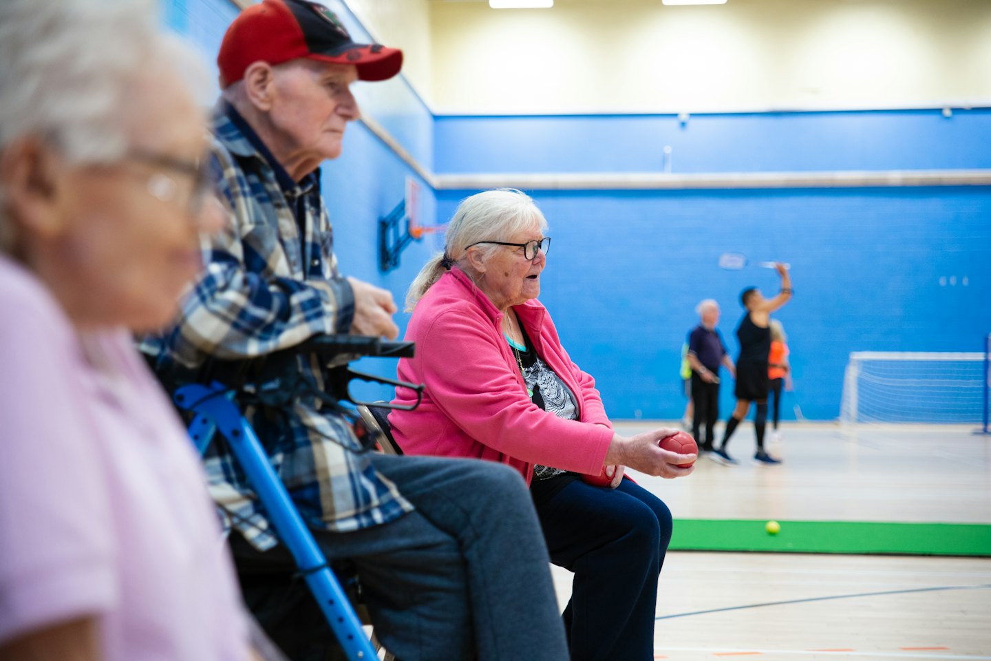 Seniors playing badminton and bocce ball in a gymnasium.